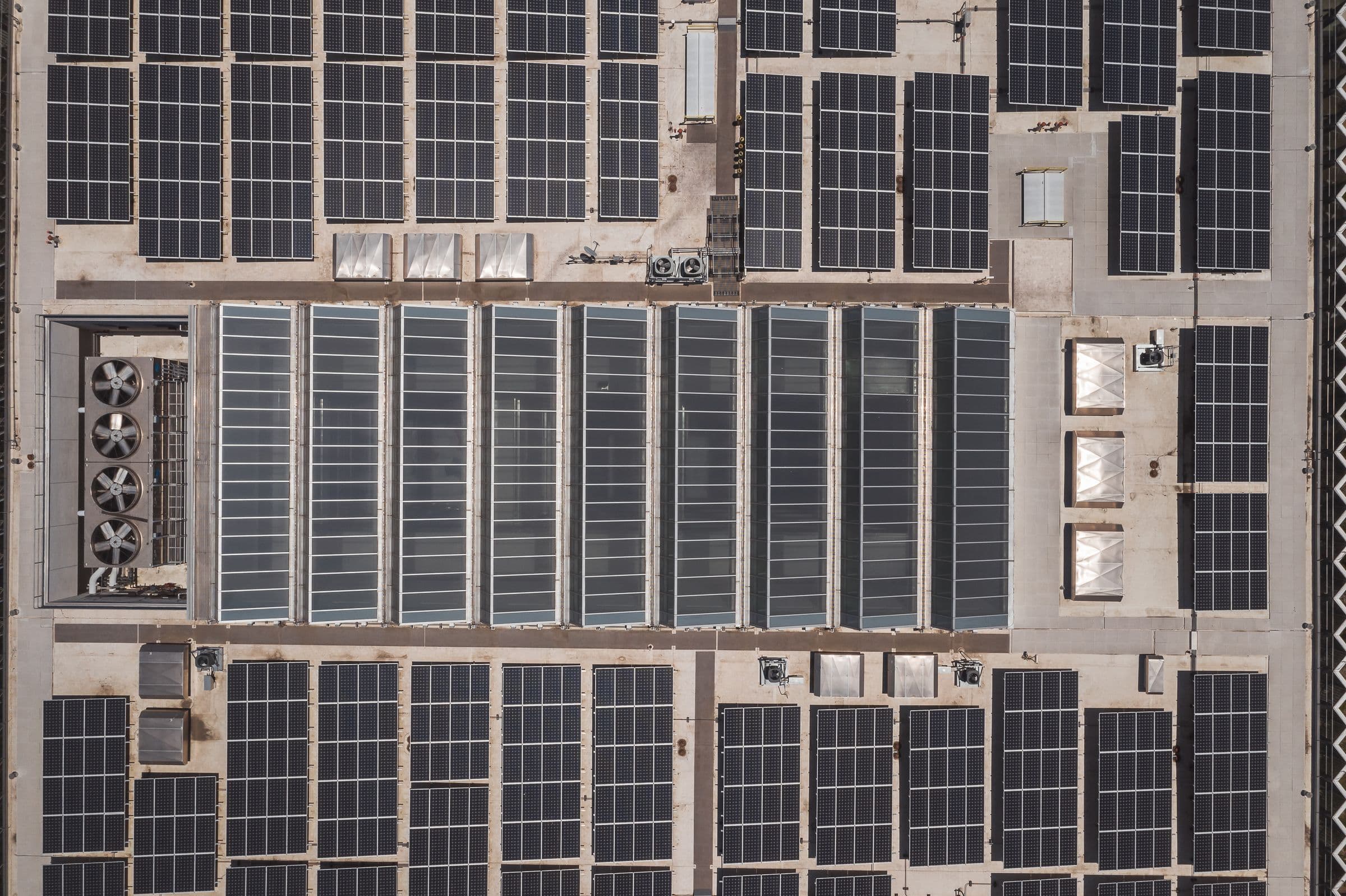 Vue aérienne de la toiture d’un entrepôt logistique couverte de larges rangées de panneaux solaires.